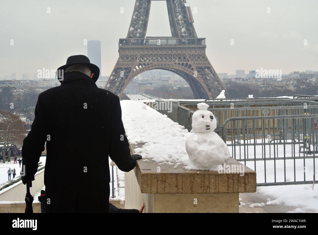 Snow in Paris. Snowman. Trocadéro Square. An elderly man carefully descends the slippery steps of the stairs. Stock Photo