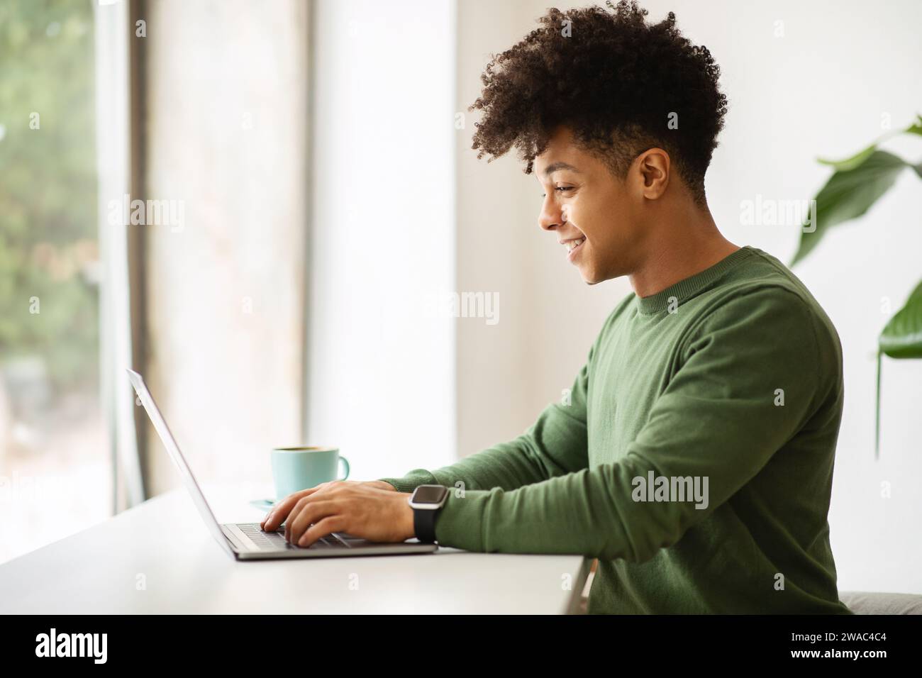 Side view young black man working at cozy cafe Stock Photo