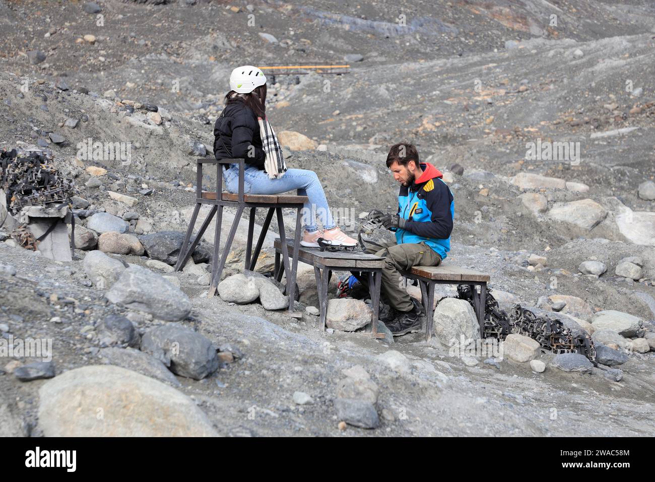 A ice trekking guide helping a visitor put ice crampons on her shoes.Perito Moreno Glacier.El Calafate. Patagonia.Argentina Stock Photo