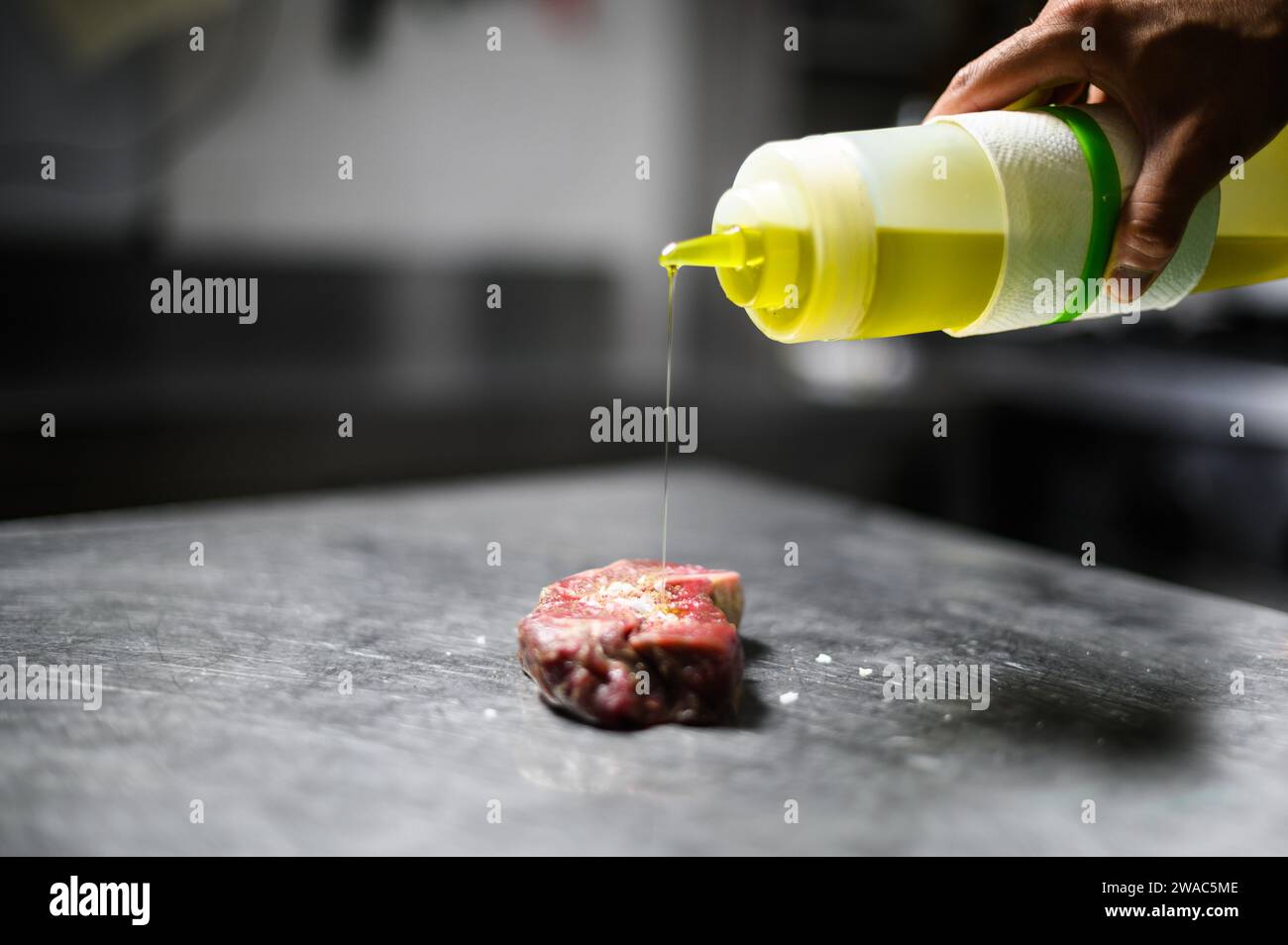 Chef pouring oil on a raw steak Stock Photo