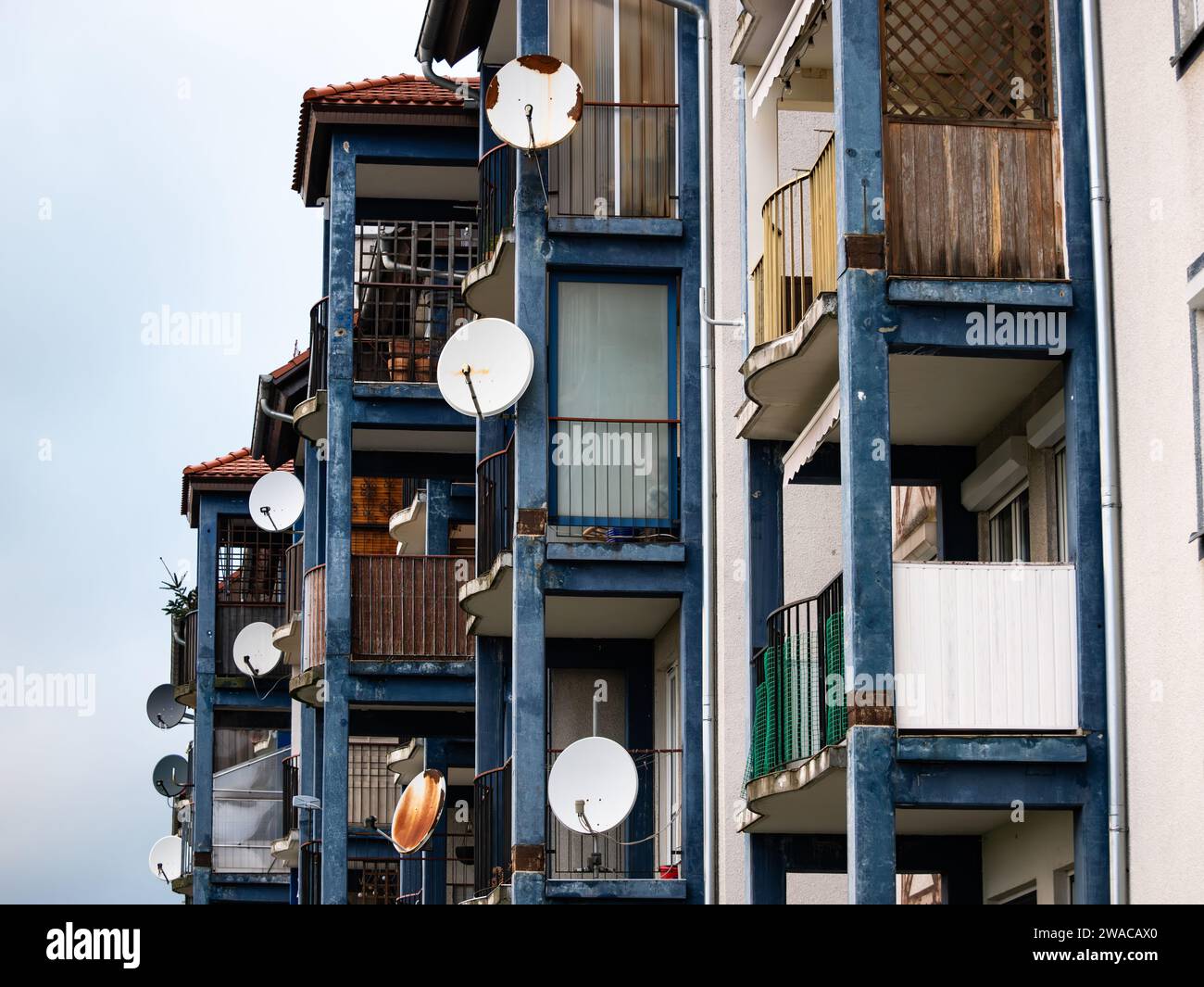 Satellite dishes mounted to balconies of a big apartment building. Technology to receive tv channels. The residential district seems to be poor. Stock Photo