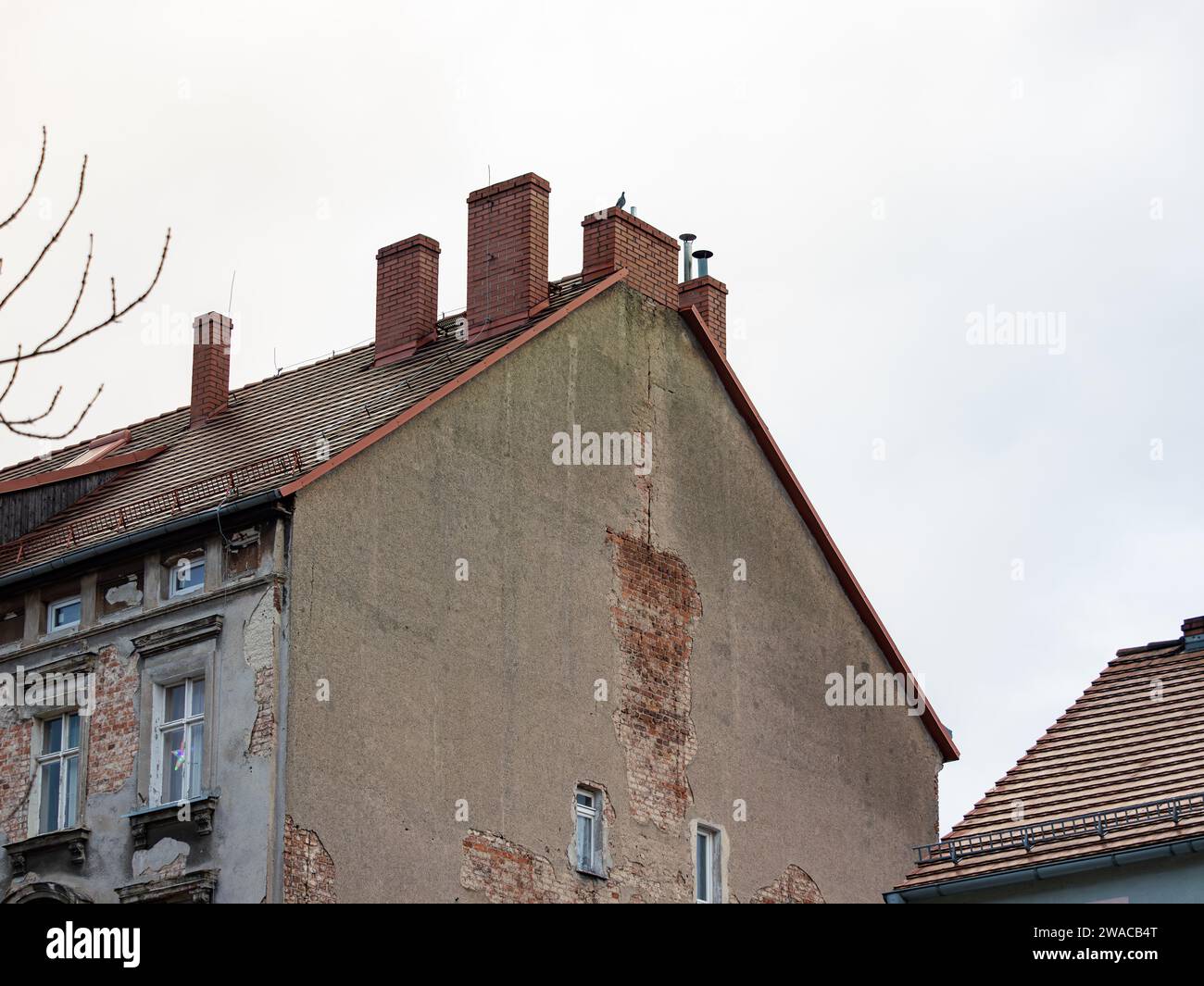 Broken tenement building exterior of an apartment house. Plaster is peeling off the brick wall. The facade is in a bad condition and needs renovation. Stock Photo