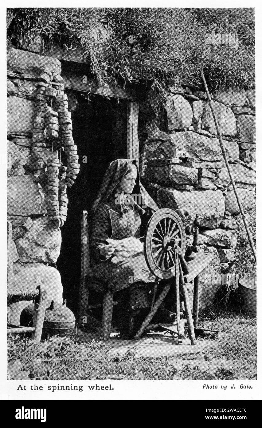 halftone of a woman operating a spinning wheel in the doorway of her home, circa 1913 Stock Photo