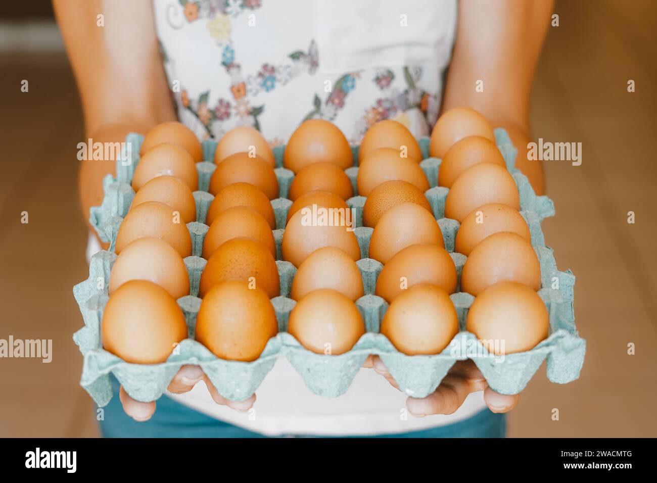 A woman seen holding freerange red eggs on a tray. The egg has