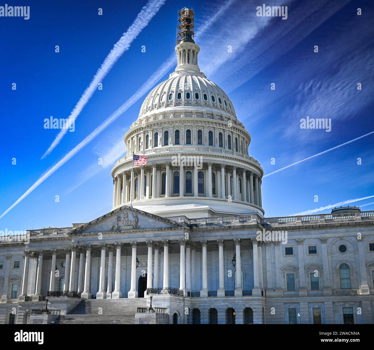 A sky of contrails criss-cross the sky above the US Capitol Building in Washington DC making for a dramatic presentation for a controversial landmark Stock Photo