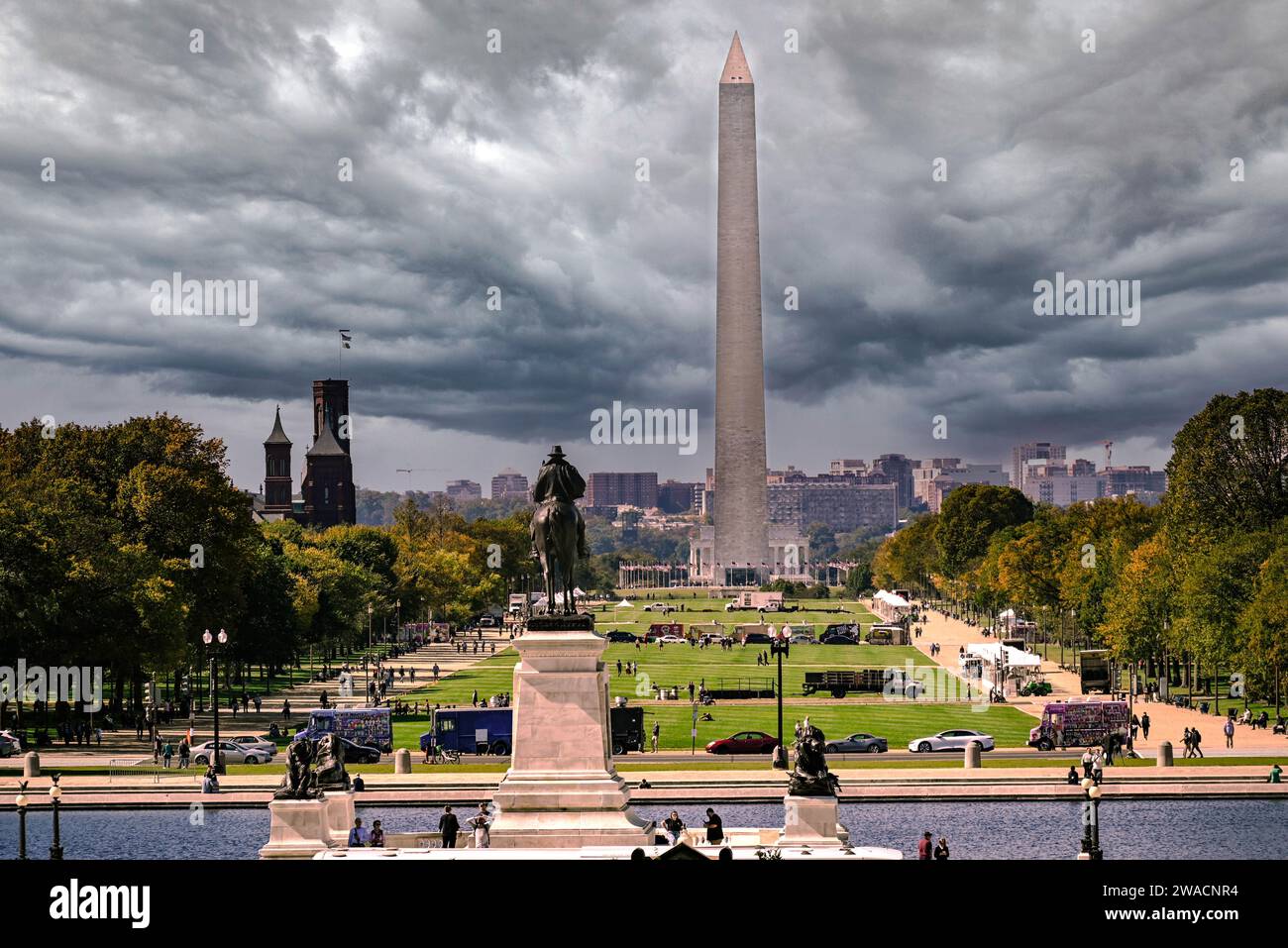 View of the Mall looking towards the Washington Monument  under stormy skies with statues and tourists, the old Smithsonian building and food trucks i Stock Photo