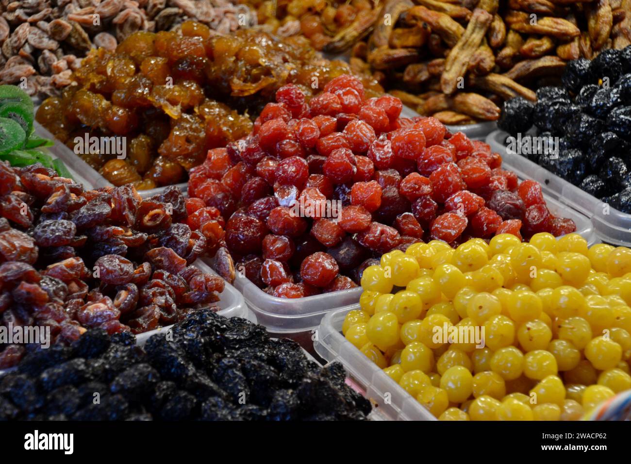 Close up candied fruits sold as desserts by roadside market stall traders in Hanoi, Vietnam include grapes, dates, berries and figs all sugar glazed Stock Photo