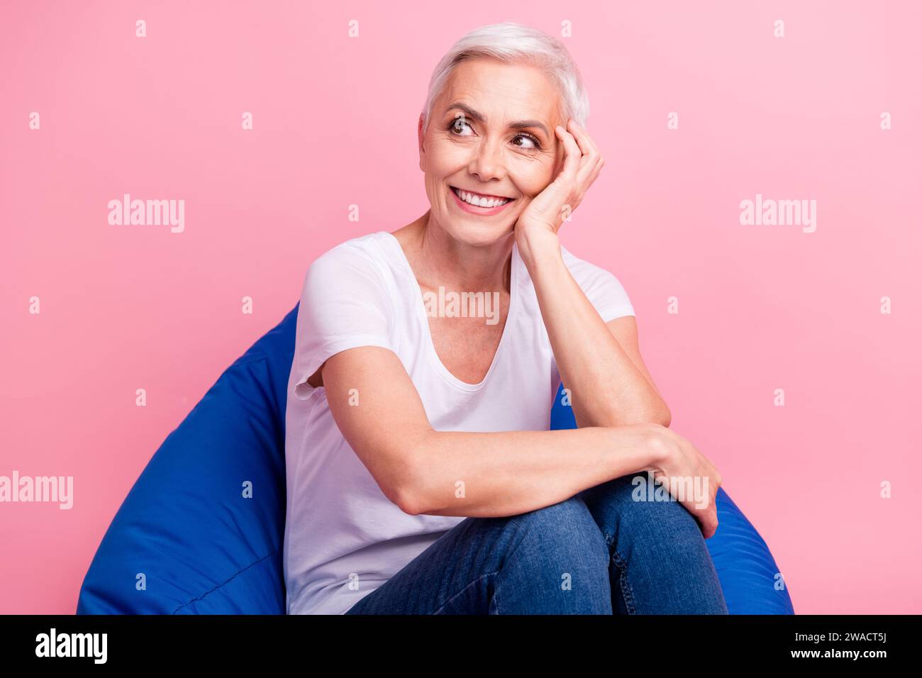 Portrait of dreamy optimistic person dressed stylish t-shirt leep arm on cheek look at promo empty space isolated on pink background Stock Photo