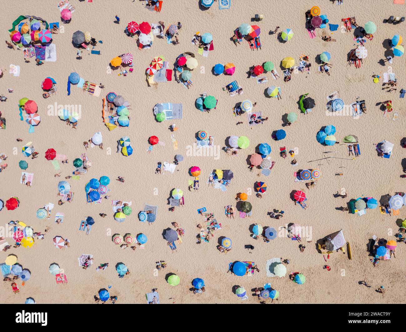 Top down aerial view of people relaxing at the beach on a sunny day in Costa da Caparica near Lisbon, Portugal. Stock Photo
