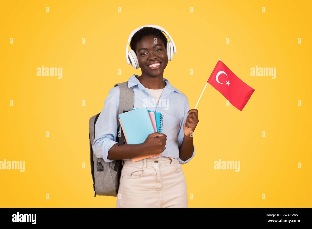 Smiling teen african american woman student in wireless headphones, with books, flag of China Stock Photo