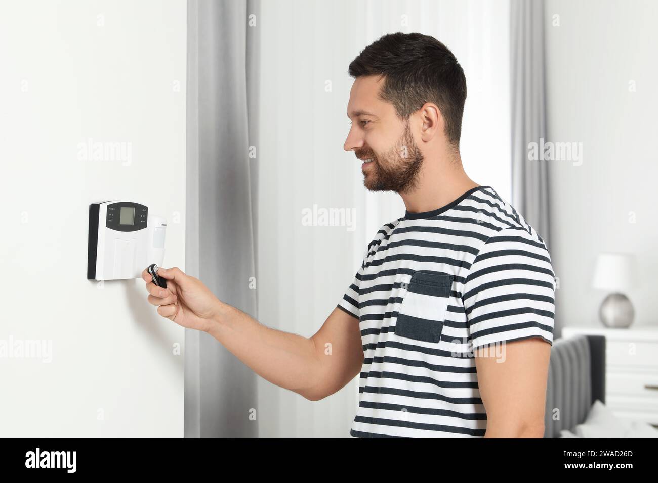 Home security system. Man using alarm key fob indoors Stock Photo