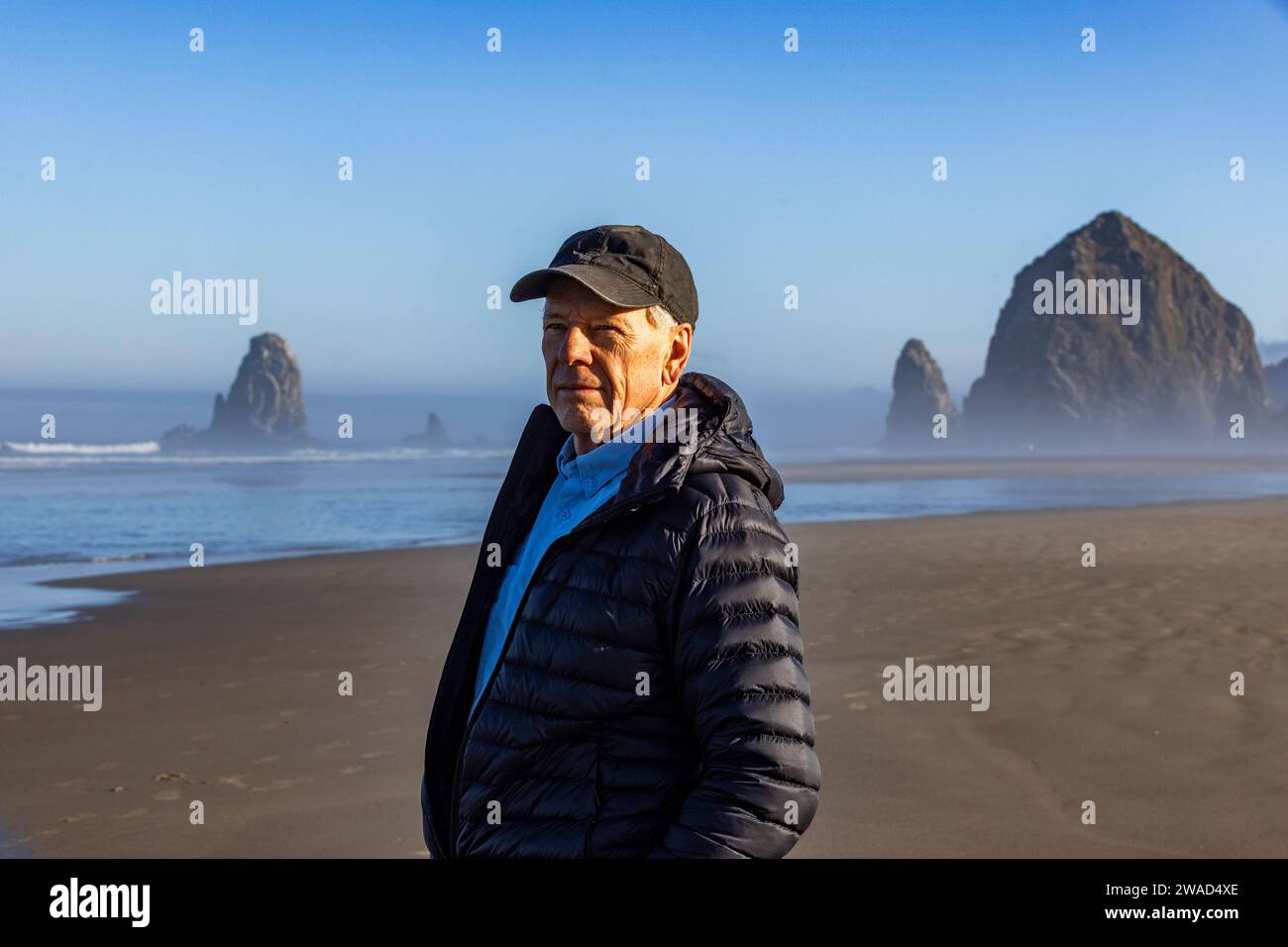 USA, Oregon, Portrait of man standing near Haystack Rock at Cannon Beach in morning mist Stock Photo