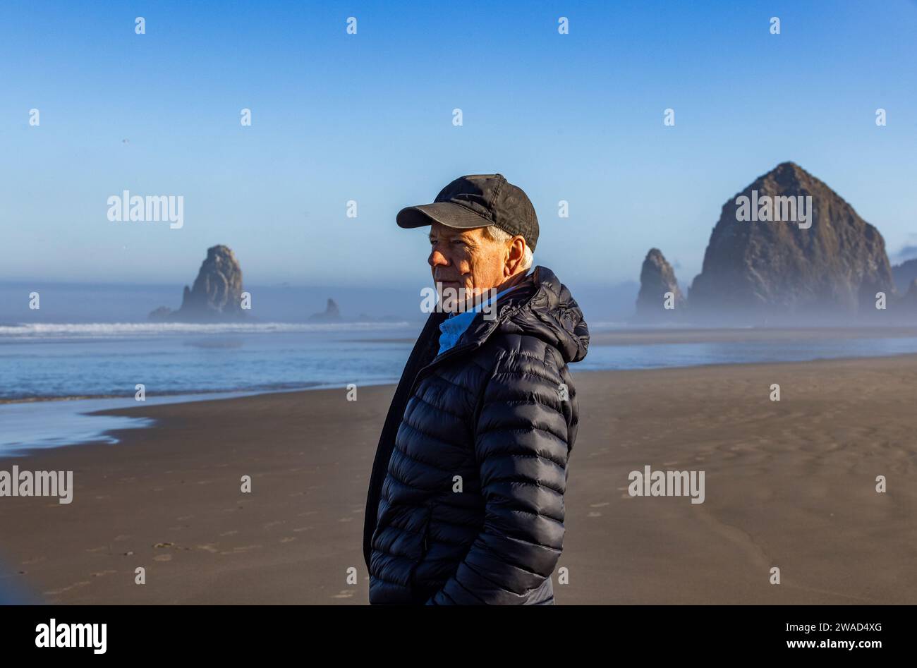 USA, Oregon, Man standing near Haystack Rock at Cannon Beach in morning mist Stock Photo