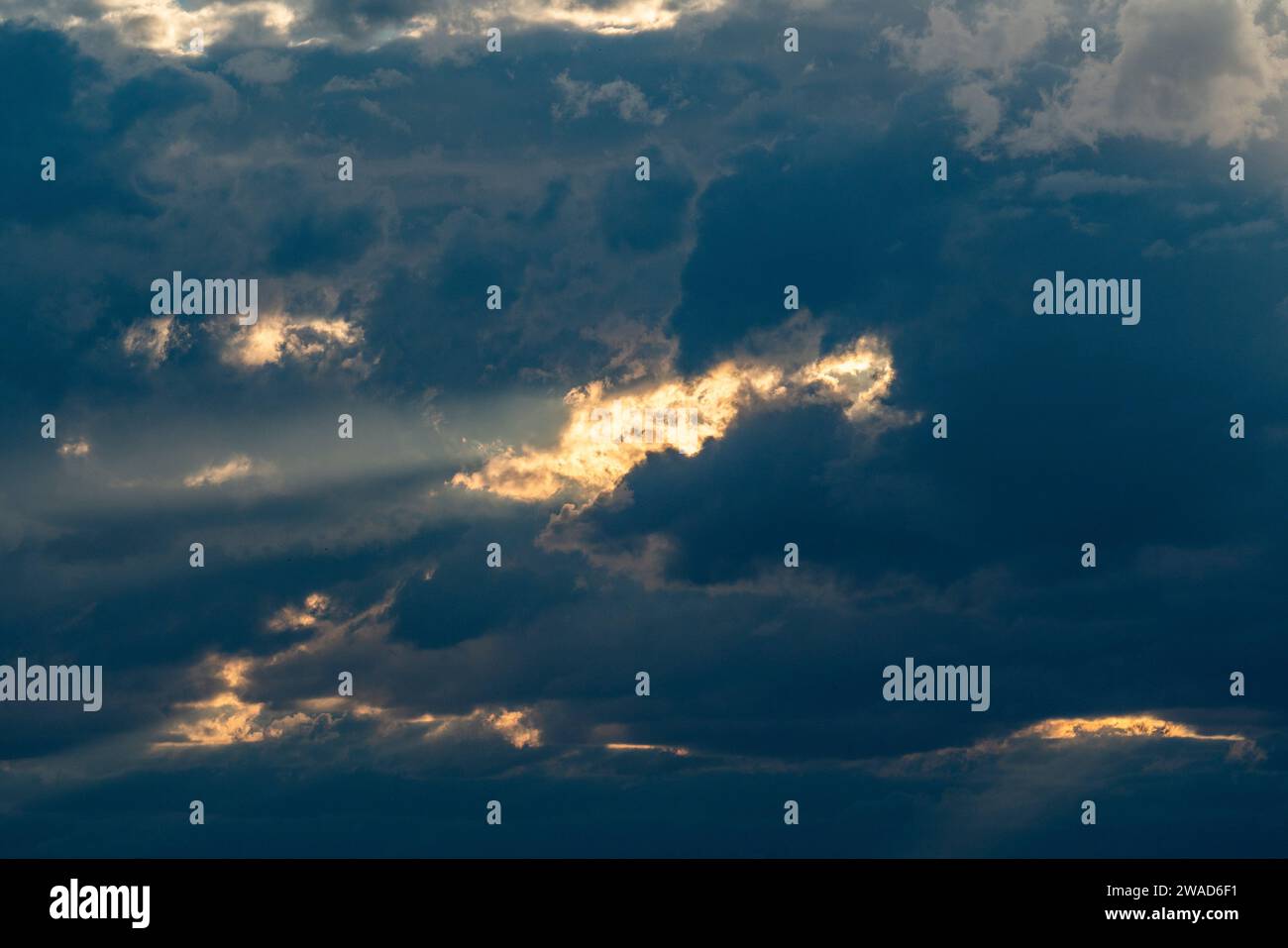 Sunlight shining through dark clouds at sunset Stock Photo