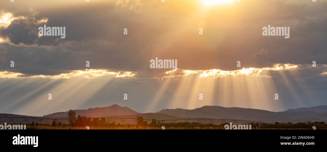 Rays from setting sun shining on fields and hills Stock Photo