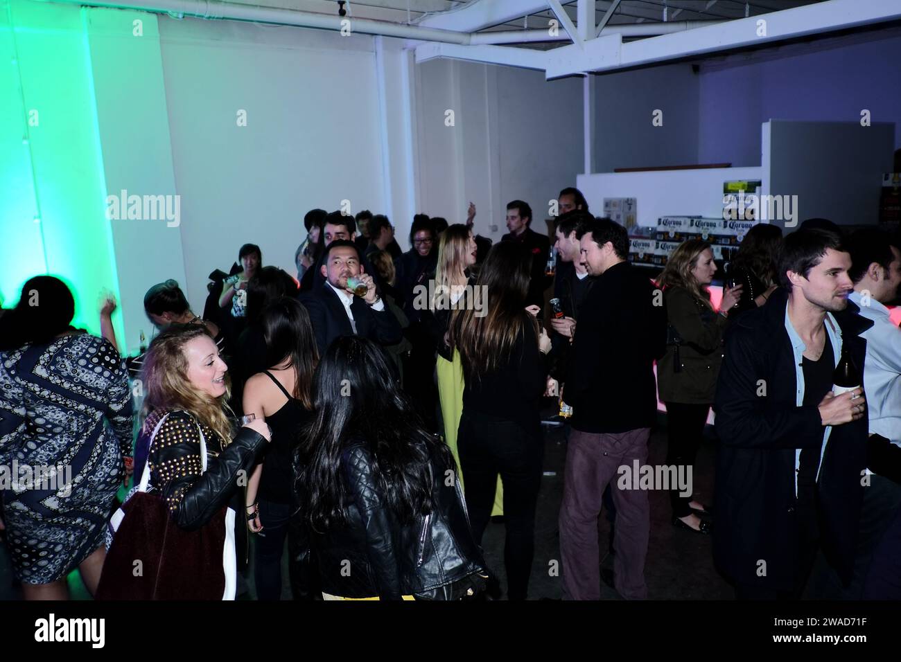 Dancing at a Sydney warehouse art opening event, pastel colours, green on white walls, pop up bar and nightlife photographed by Street Fashion Sydney Stock Photo