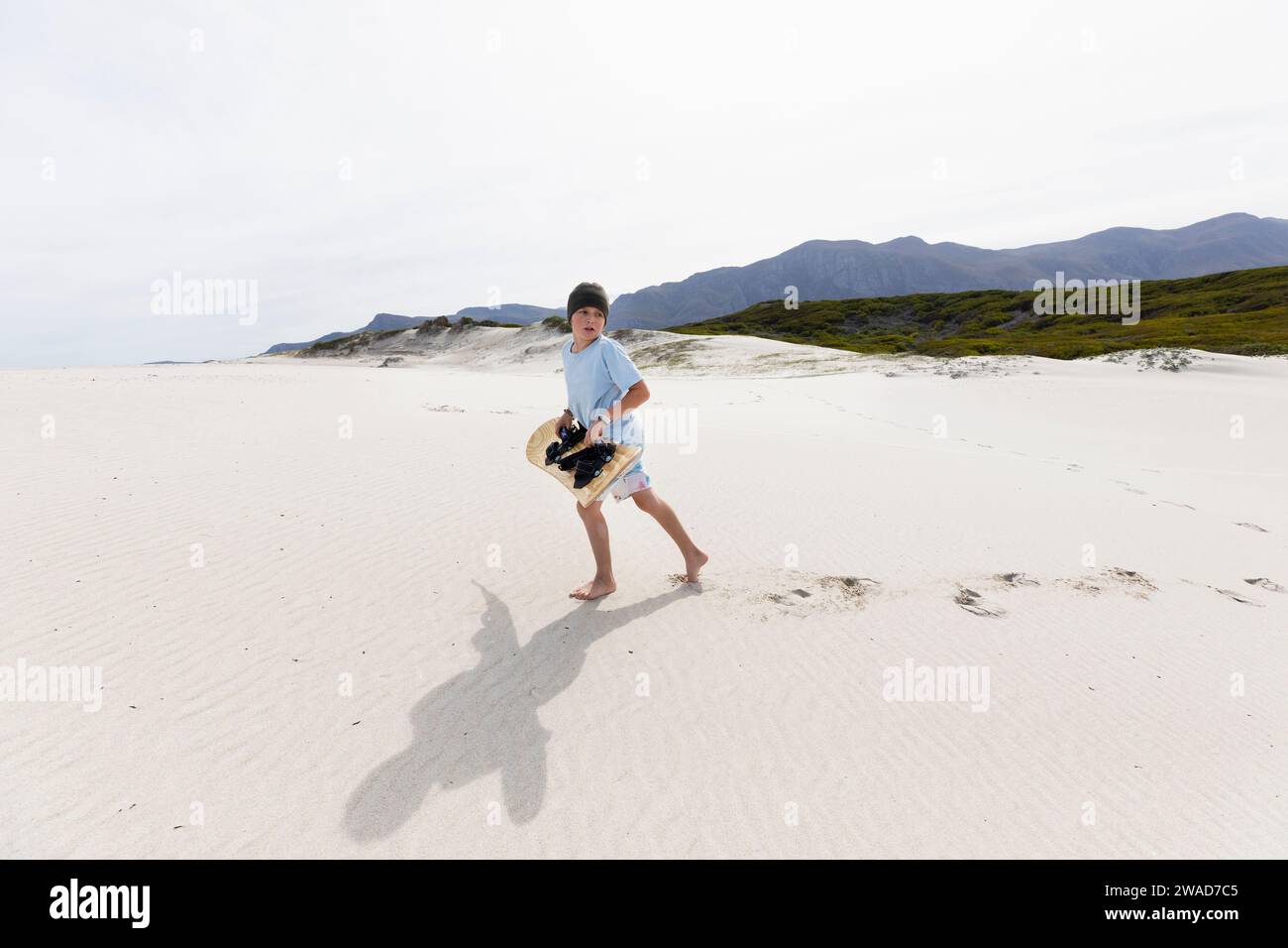 Boy (10-11) carrying surfboard in Walker Bay Nature Reserve Stock Photo