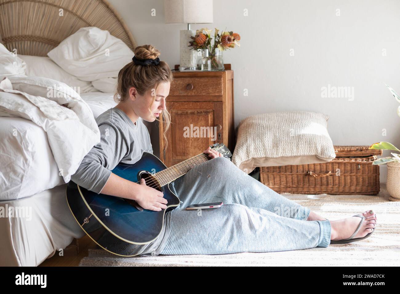 Teenage girl (16-17) playing guitar in bedroom Stock Photo