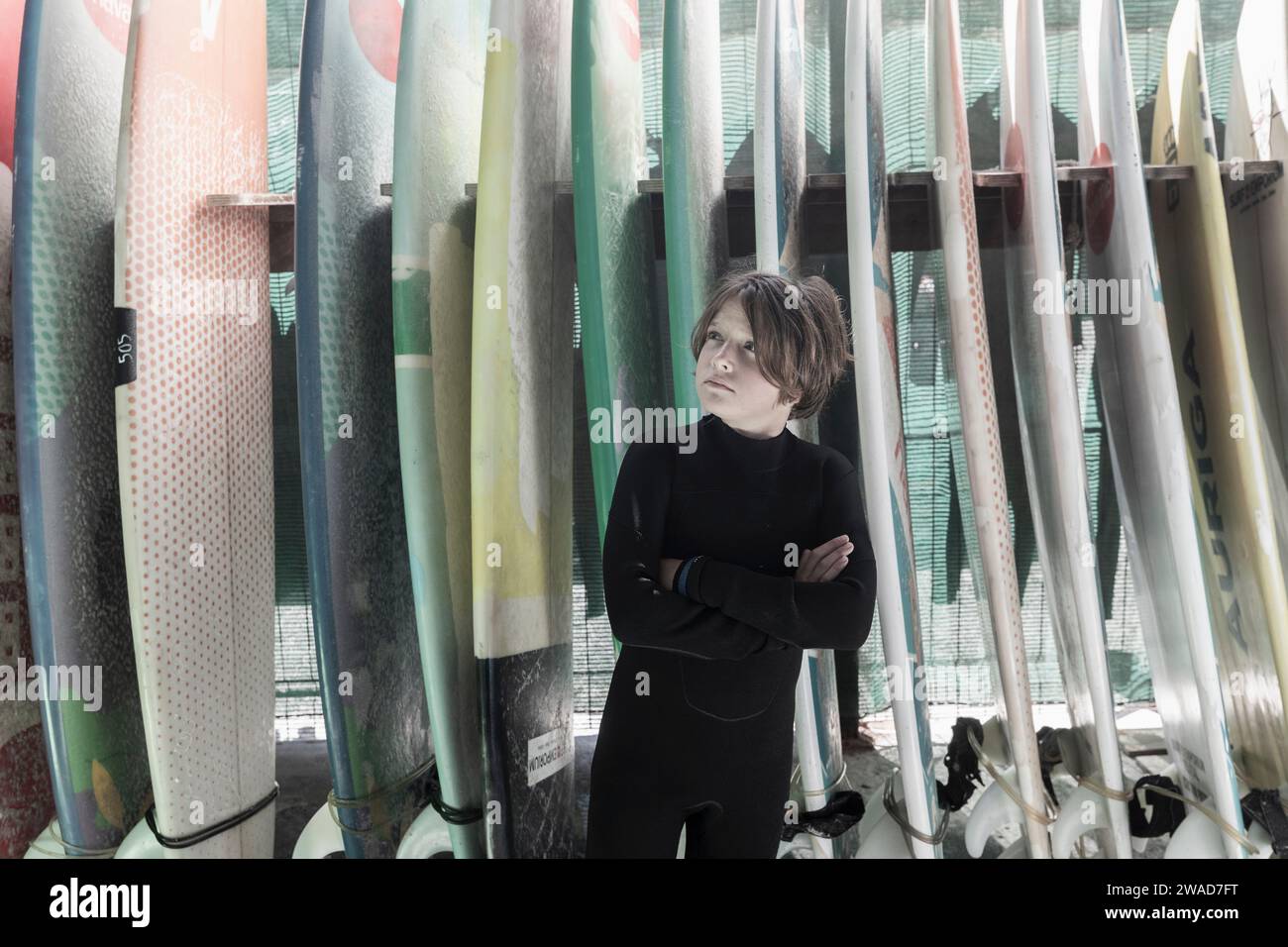 Boy (10-11) posing in front of surfboards Stock Photo