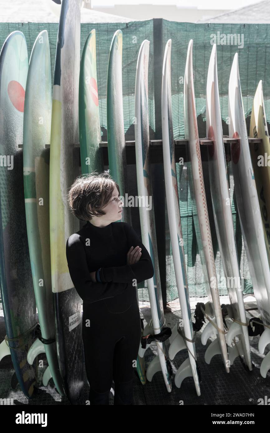 Boy (10-11) posing in front of surfboards Stock Photo