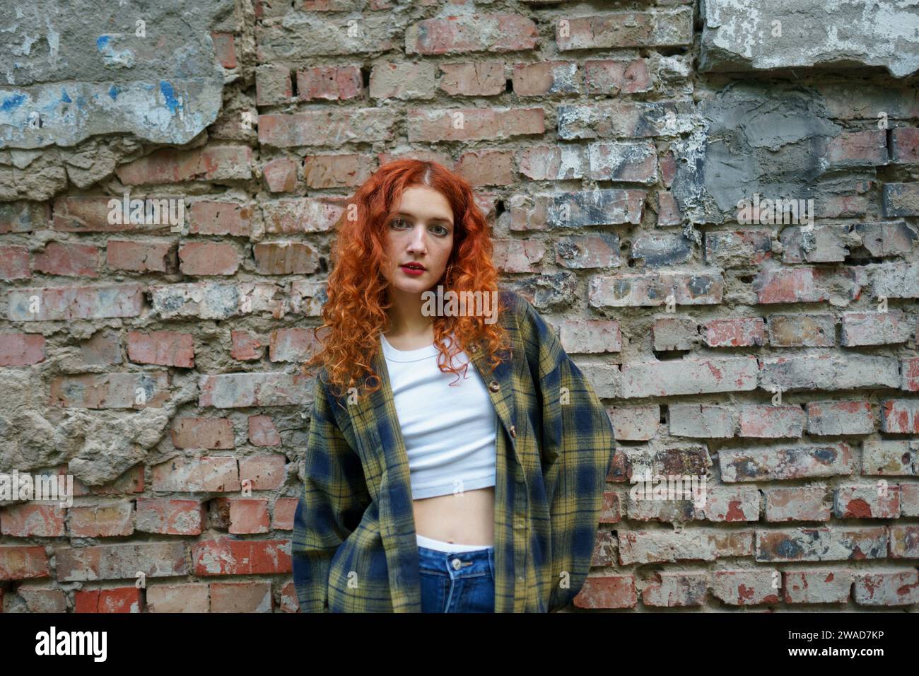 Redhaired woman posing next to old brick house Stock Photo