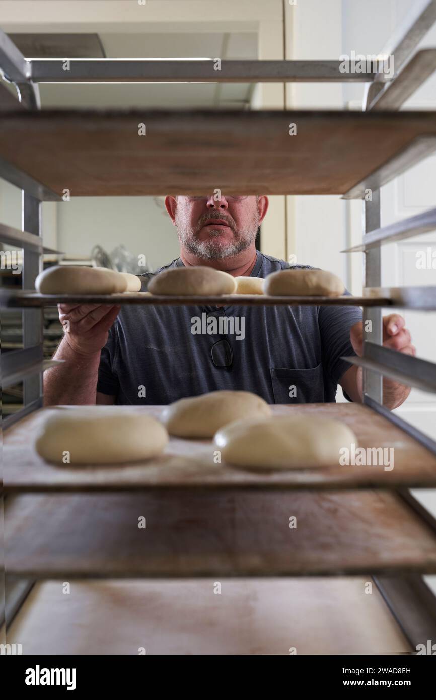 Baker standing with bread dough on tray Stock Photo