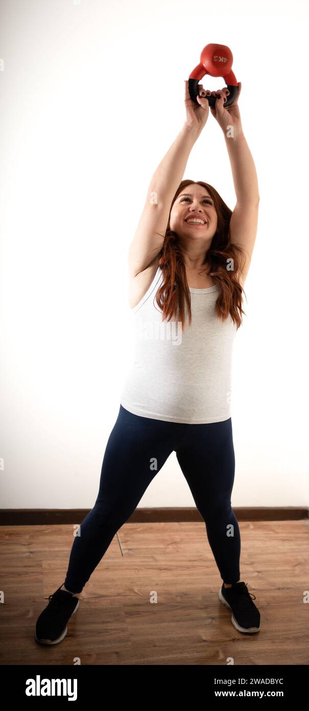 redhead woman doing exercises with a kettlebell Stock Photo