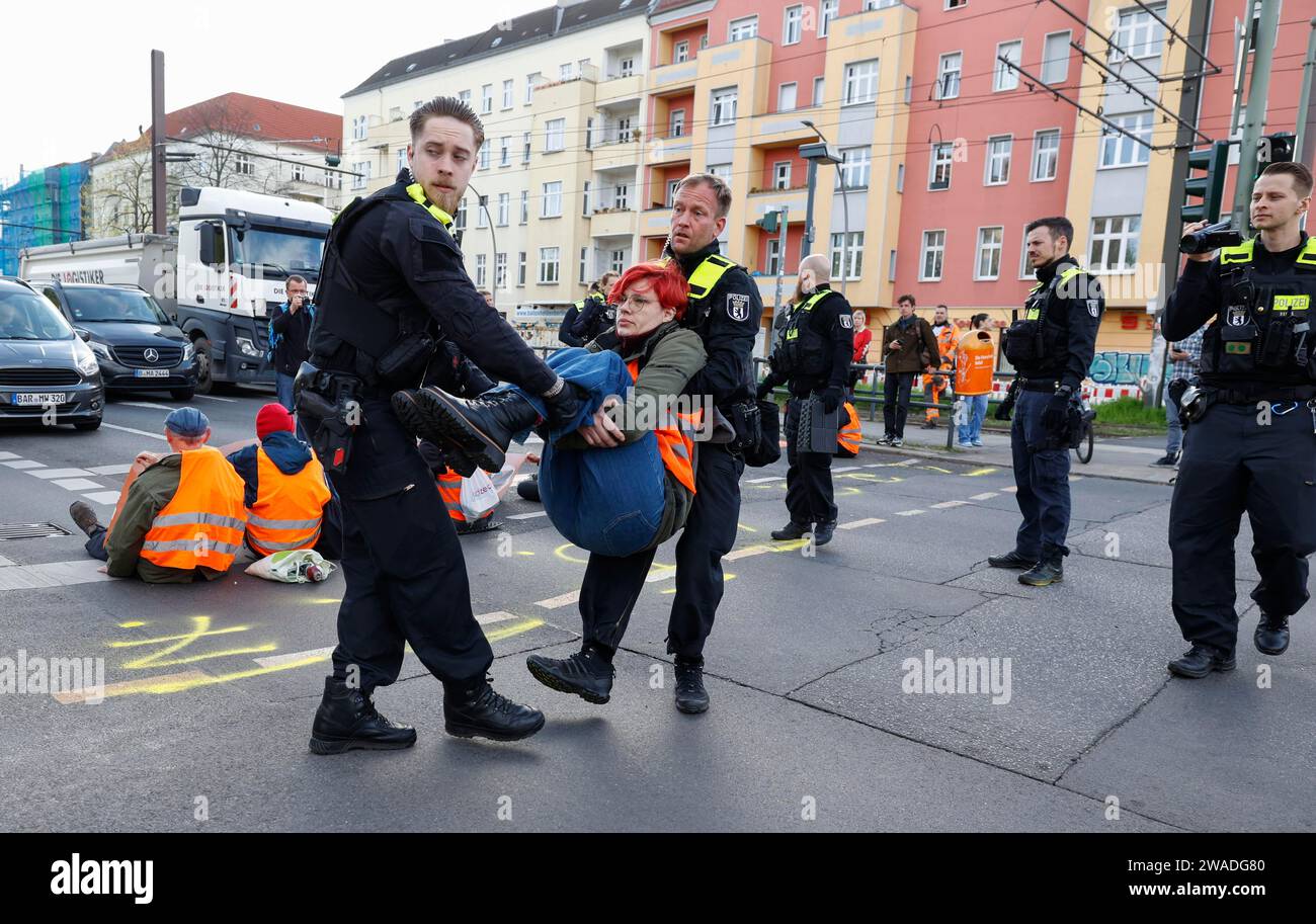 Police officers carry a Last Generation activist away from a road ...