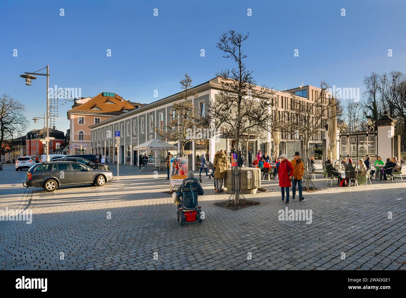 People sitting in the sun at the end of December on Residenzplatz, Kempten, Allgaeu. Bavaria, Germany Stock Photo