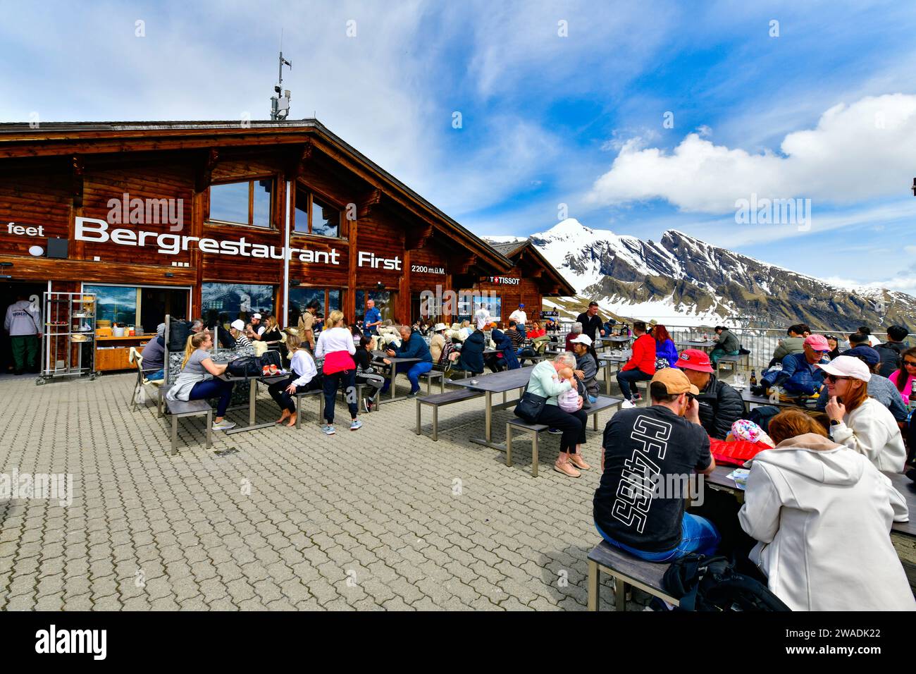 Grindelwald - May 23, 2023: Tourist at the restaurant terrace on sky cliff walk at First peak of Swiss Alps, Switzerland Stock Photo