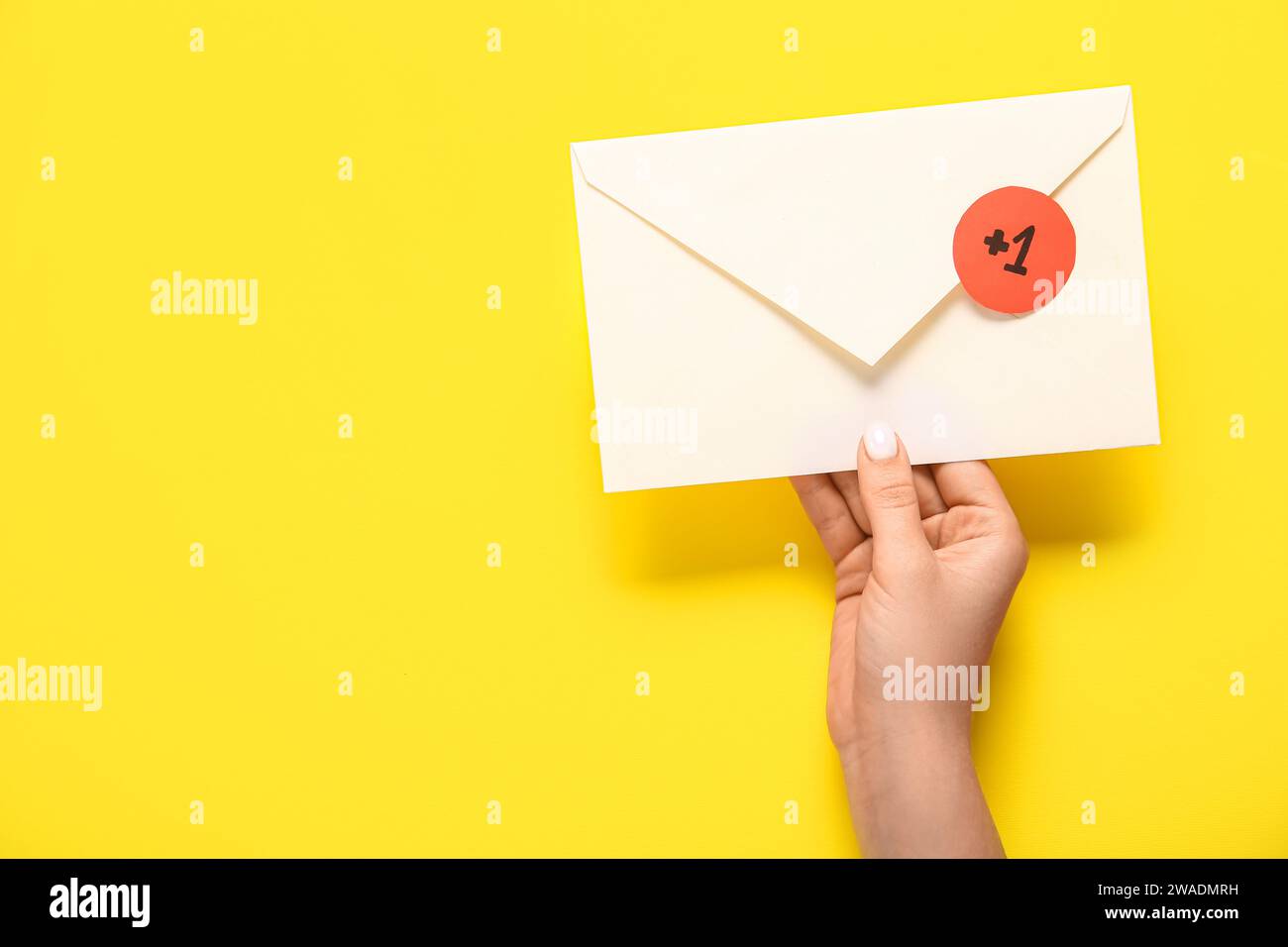 Female hand holding closed envelope with +1 icon on yellow background ...