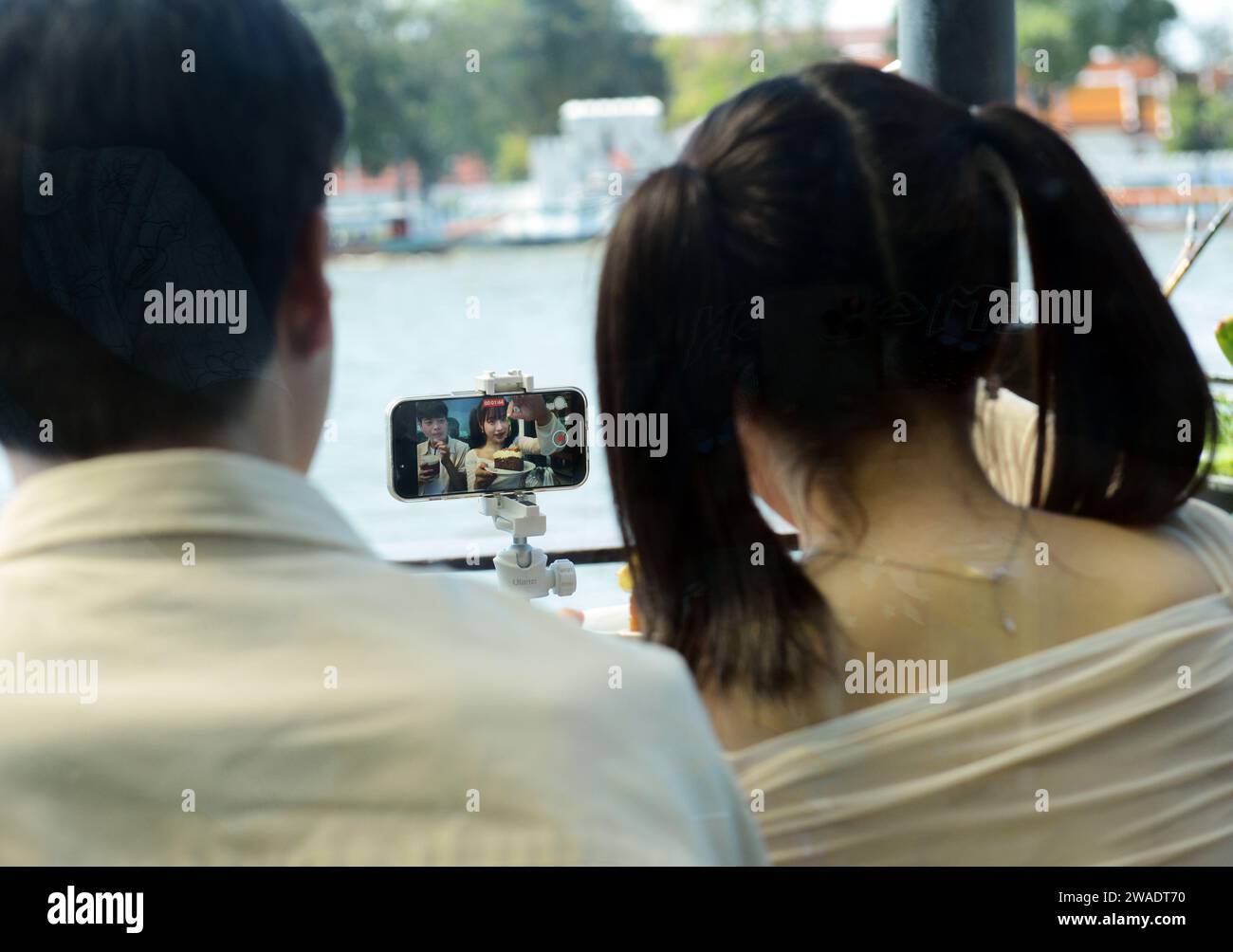 A Gen Z Asian couple filming themselves for an online vlog on their social media platform. Bangkok, Thailand. Stock Photo