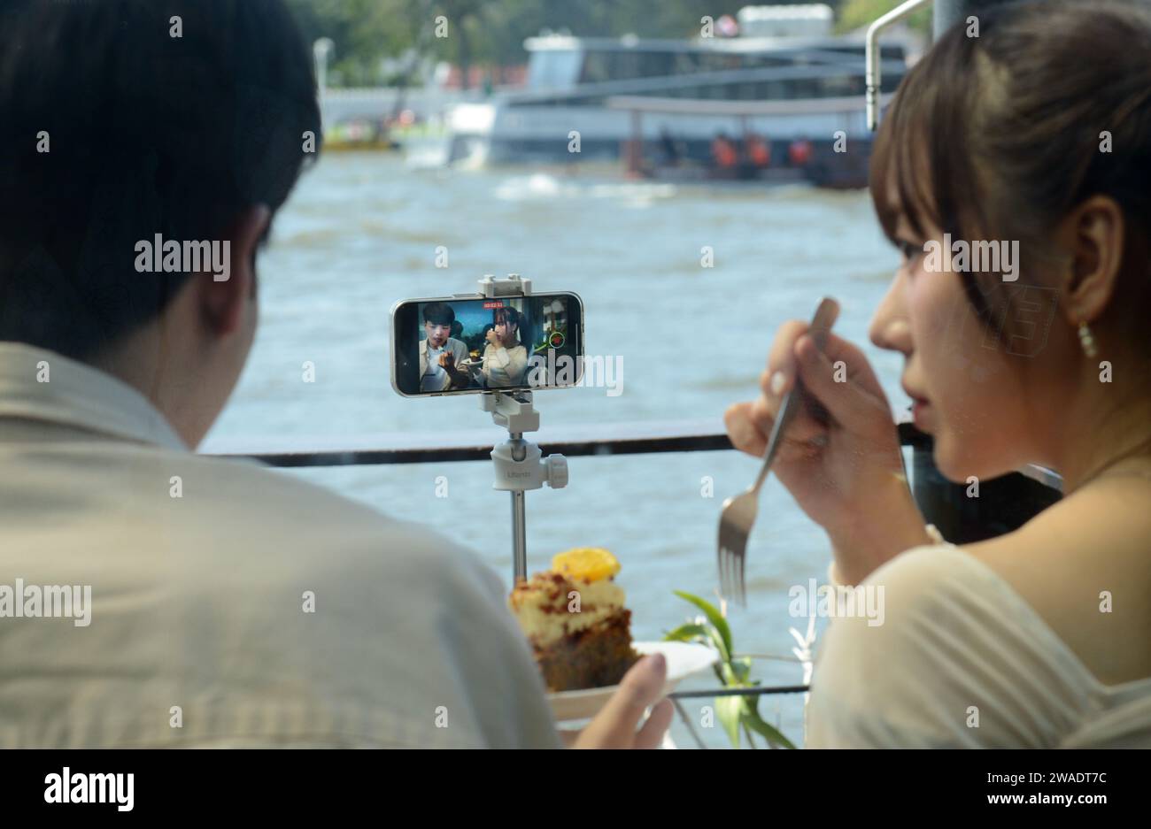 A Gen Z Asian couple filming themselves for an online vlog on their social media platform. Bangkok, Thailand. Stock Photo
