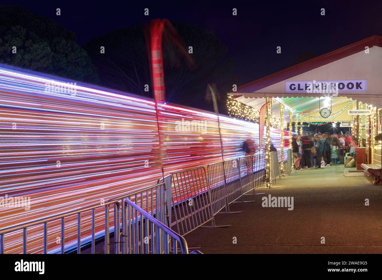 A train with Christmas lights pulls out of the station at Glenbrook Vintage Railway, Waiuku, New Zealand, creating vivid light trails Stock Photo