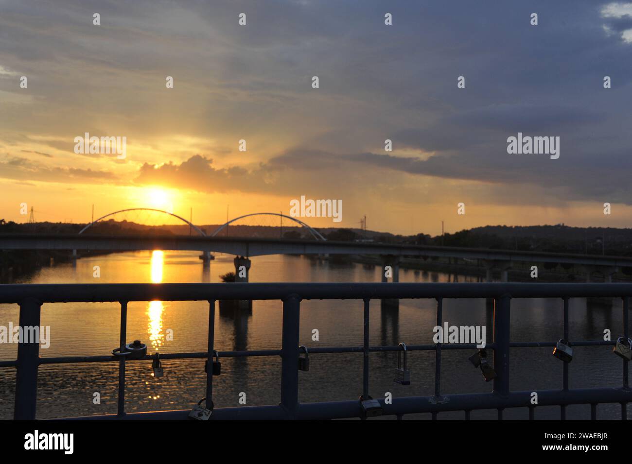 A beautiful golden sunset over a tranquil bridge with padlocks Stock Photo