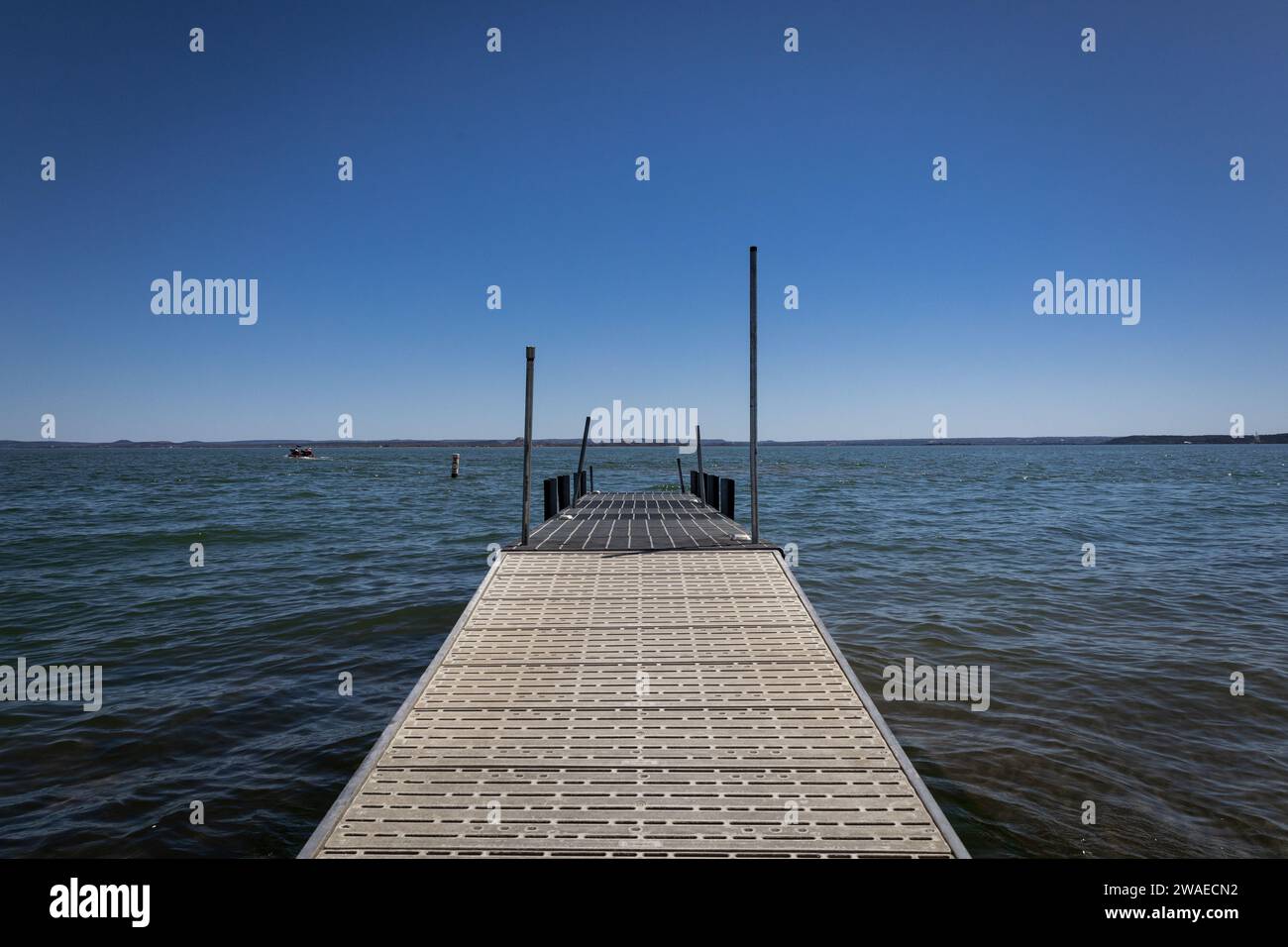A wooden boat docking pier in a tranquil lake in Texas with a cloudless, brilliant blue sky overhead Stock Photo