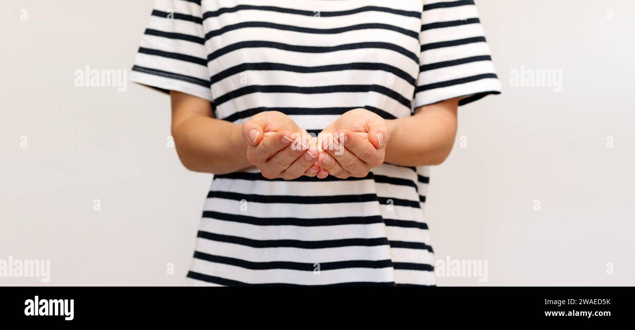 Woman in striped tee shirt holds her hands in front of her with palms up. Stock Photo