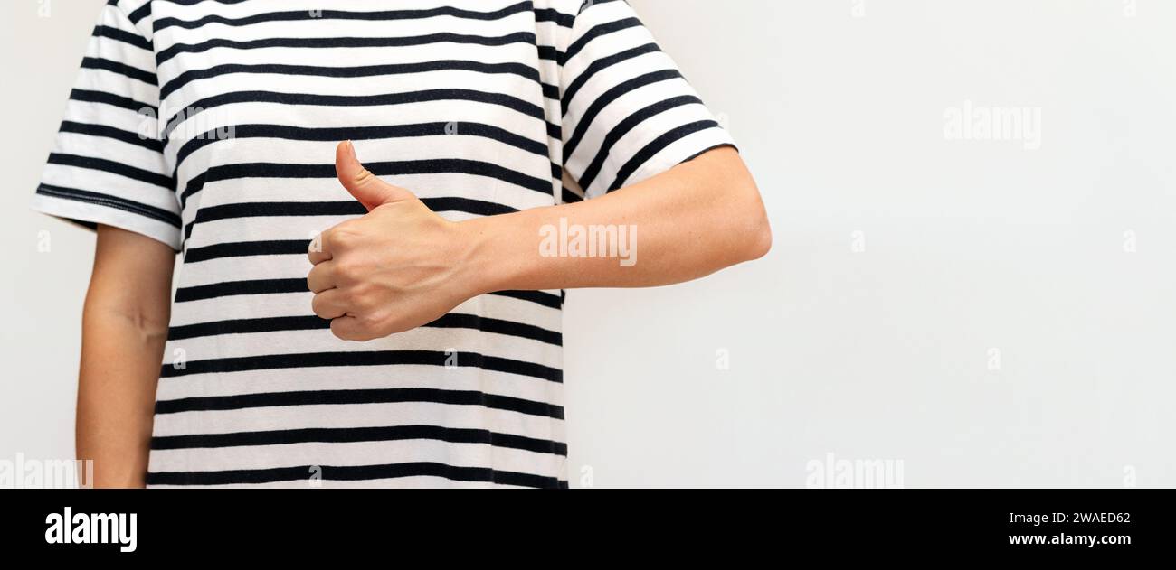 Unrecognisable female person in striped sailor t-shirt gesturing thumbs ...