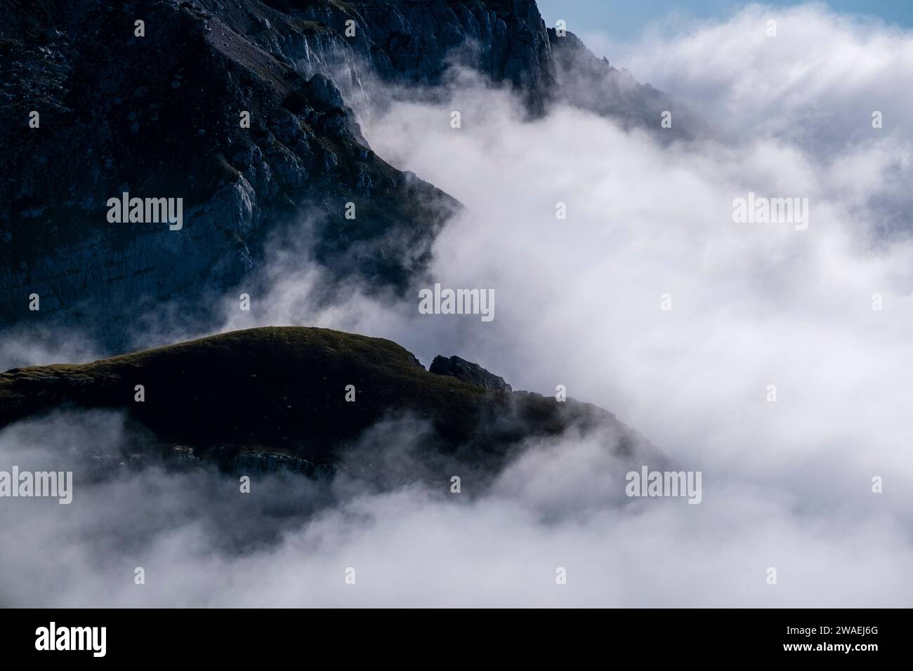 Cliffs and ridges of the mountain Piz Galin sticking out of the clouds, seen from the summit of Croz dell'Altissimo. Stock Photo
