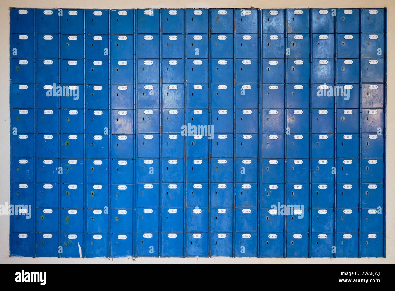 Wall of Antique numbered locked boxes. Box doors are blue with key