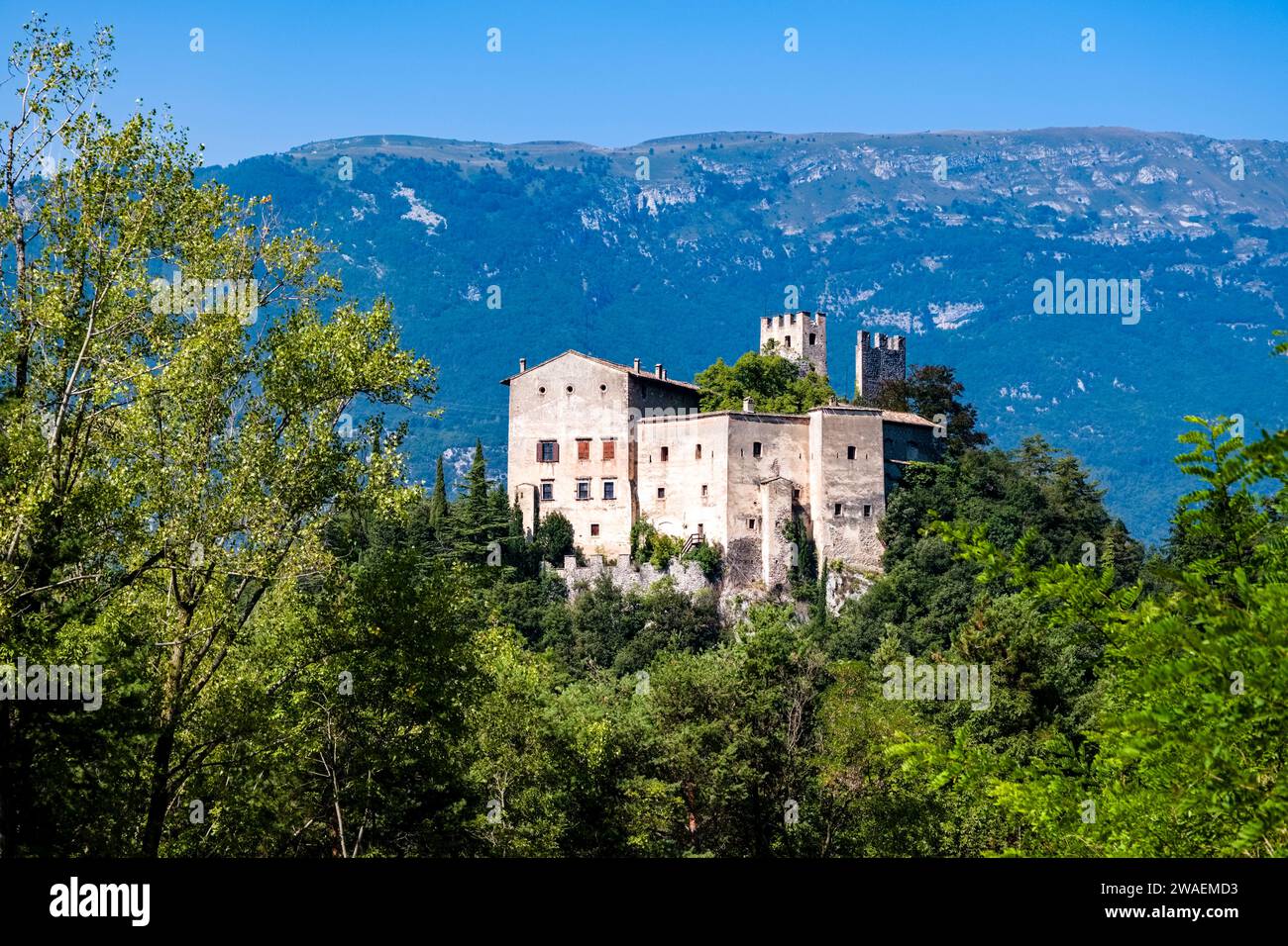 The castle Castel Toblino, built in the 14th century, situated on a peninsula of the lake Lago di Toblino, sticking out of trees. Stock Photo