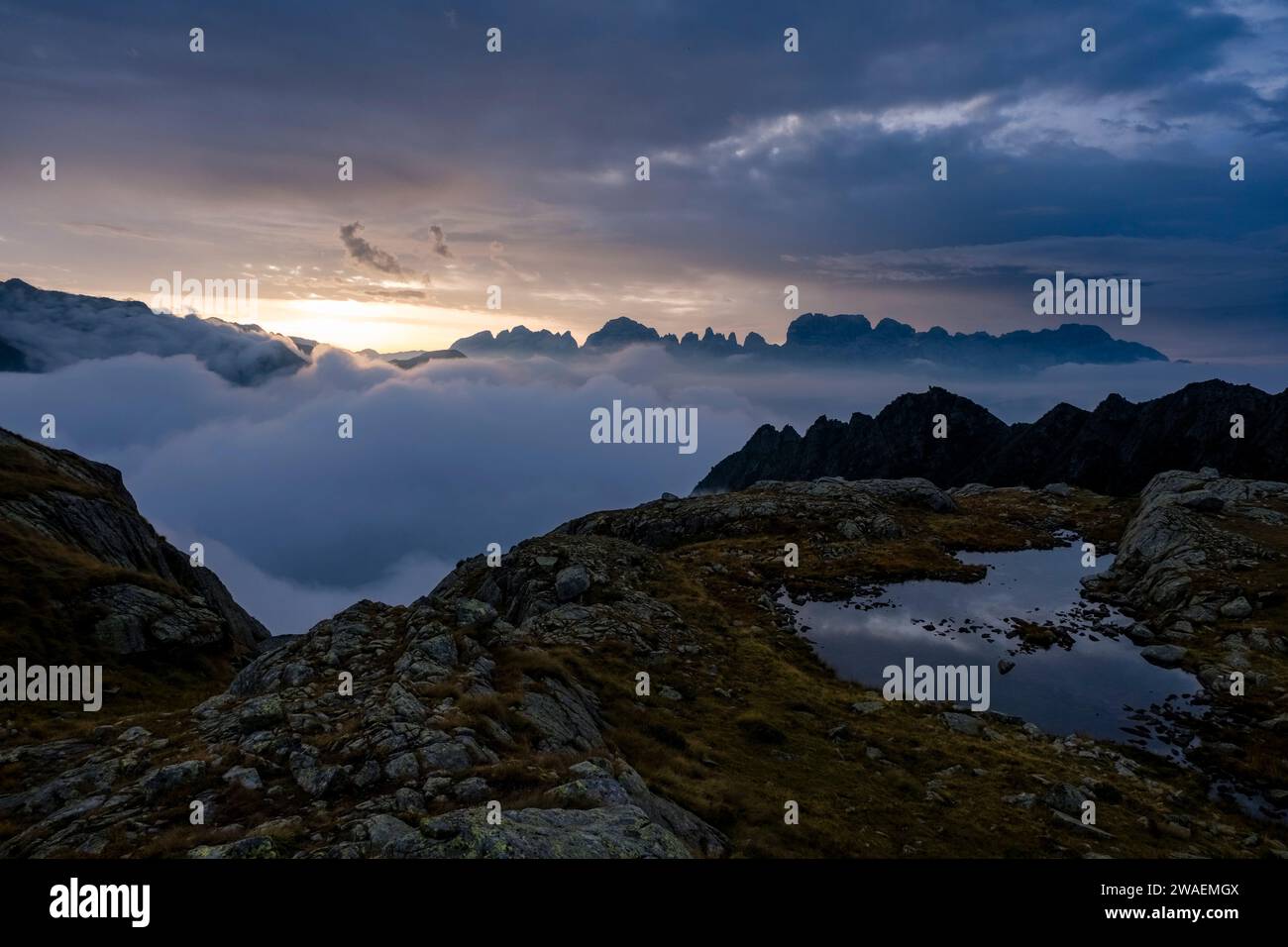 The valley of Sarca di Campiglio covered with clouds, the main range of Brenta Dolomites sticking out of the clouds, at sunrise. Stock Photo