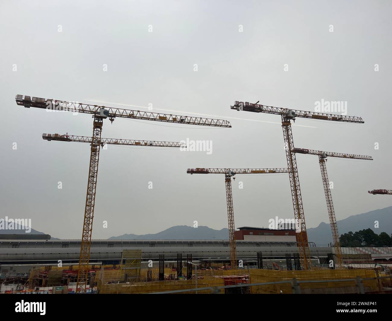 A construction site in Asia bustling with activity as multiple cranes are seen at the worksite Stock Photo