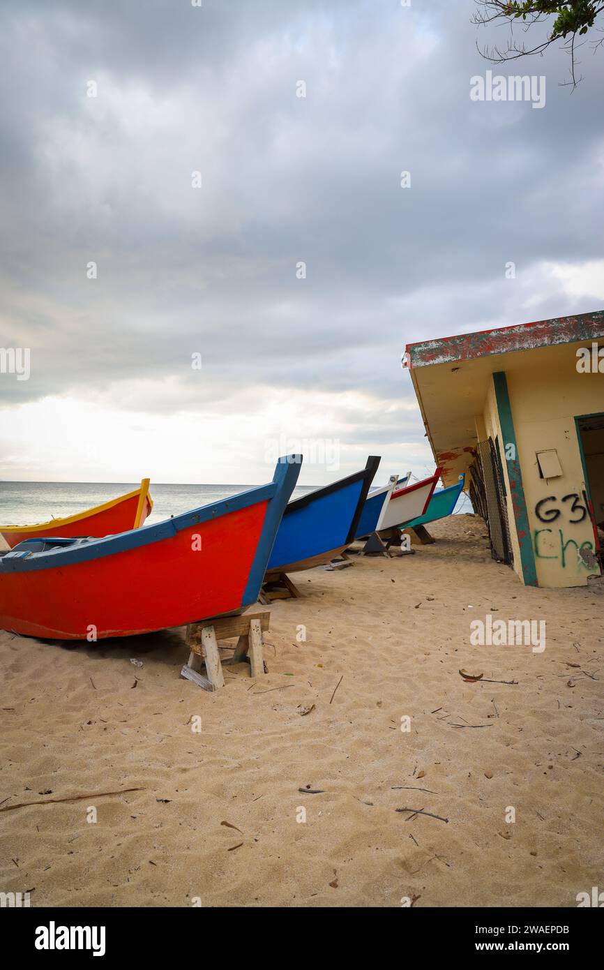 A cluster of fishing boats resting on the sandy shoreline near a destroyed building. Stock Photo