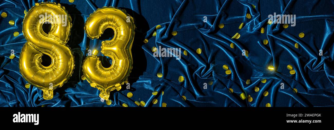 gold foil balloon number eighty three. Birthday or anniversary card with the inscription 83. blue velvet background. Anniversary celebration. Banner. Stock Photo
