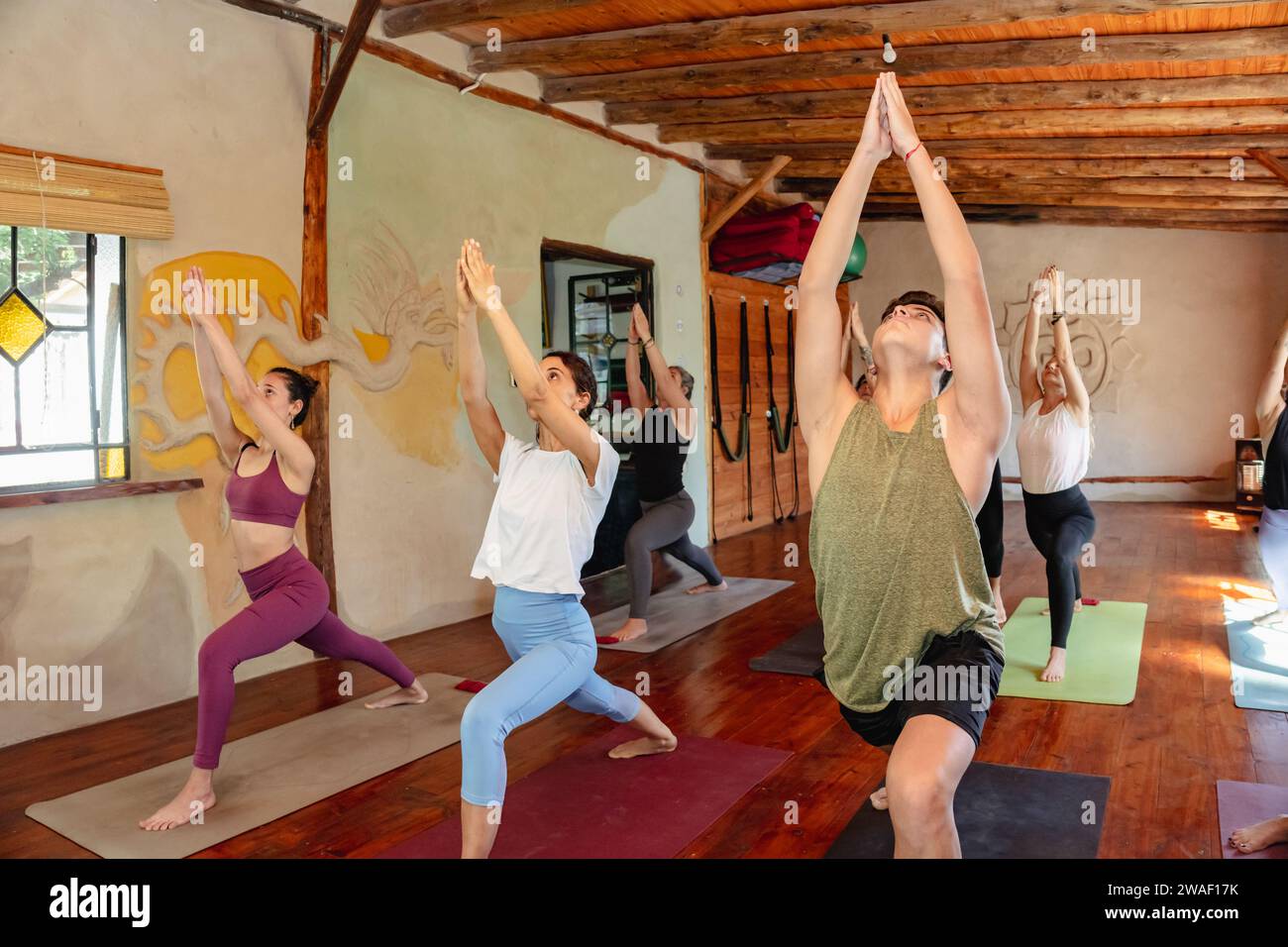 Group of people taking yoga class. Warrior Pose I (Virabhadrasana) Stock Photo