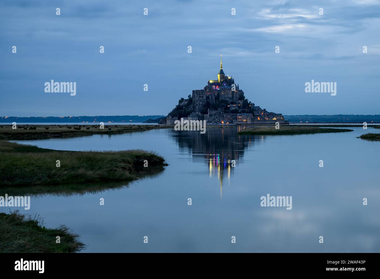 landscape with Mont Saint-Michel Abbey in the background with reflection in the water during sunset in the blue hour, Normandy, France Stock Photo