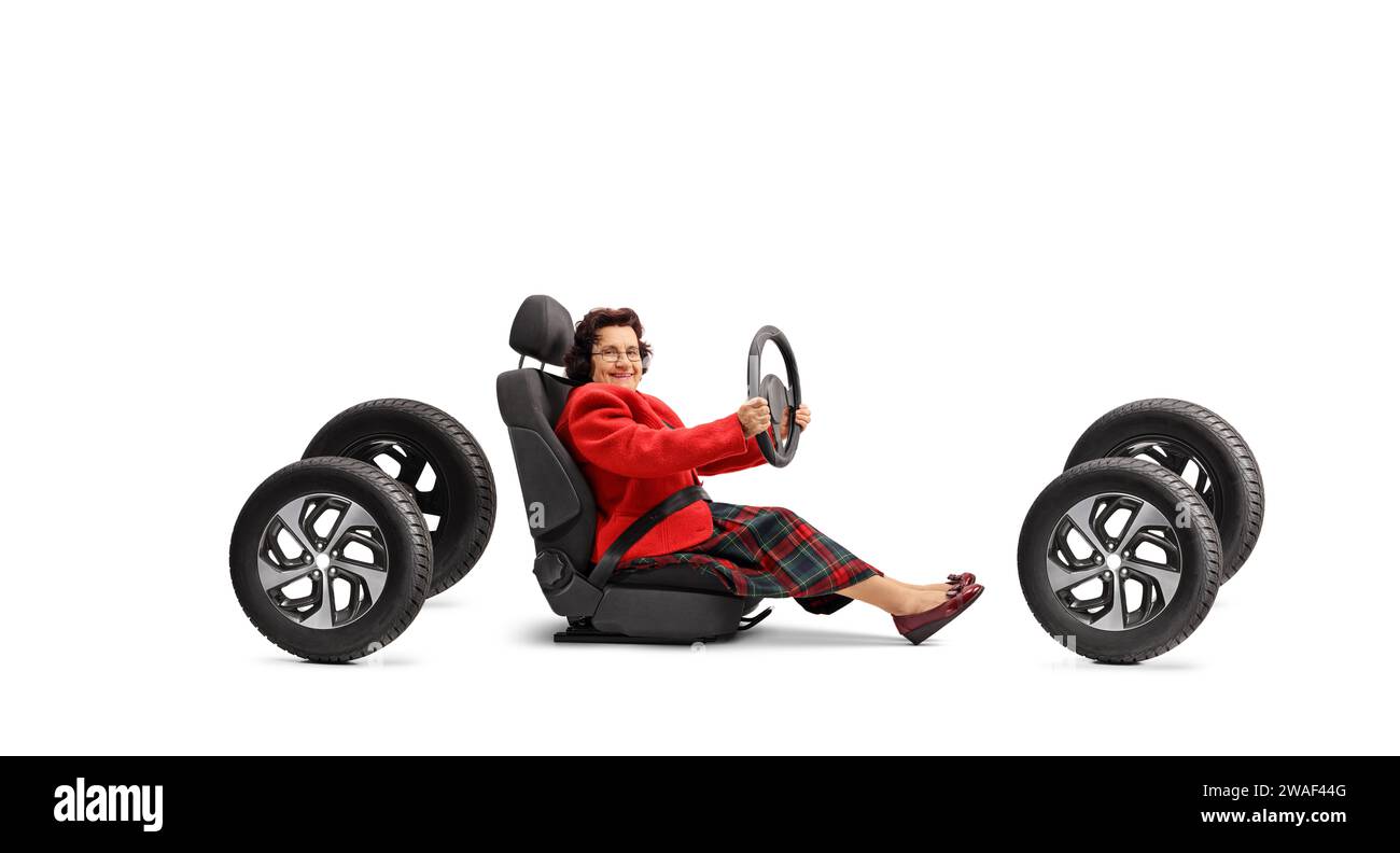 Senior woman sitting in a car seat on four tires and driving isolated on white background Stock Photo