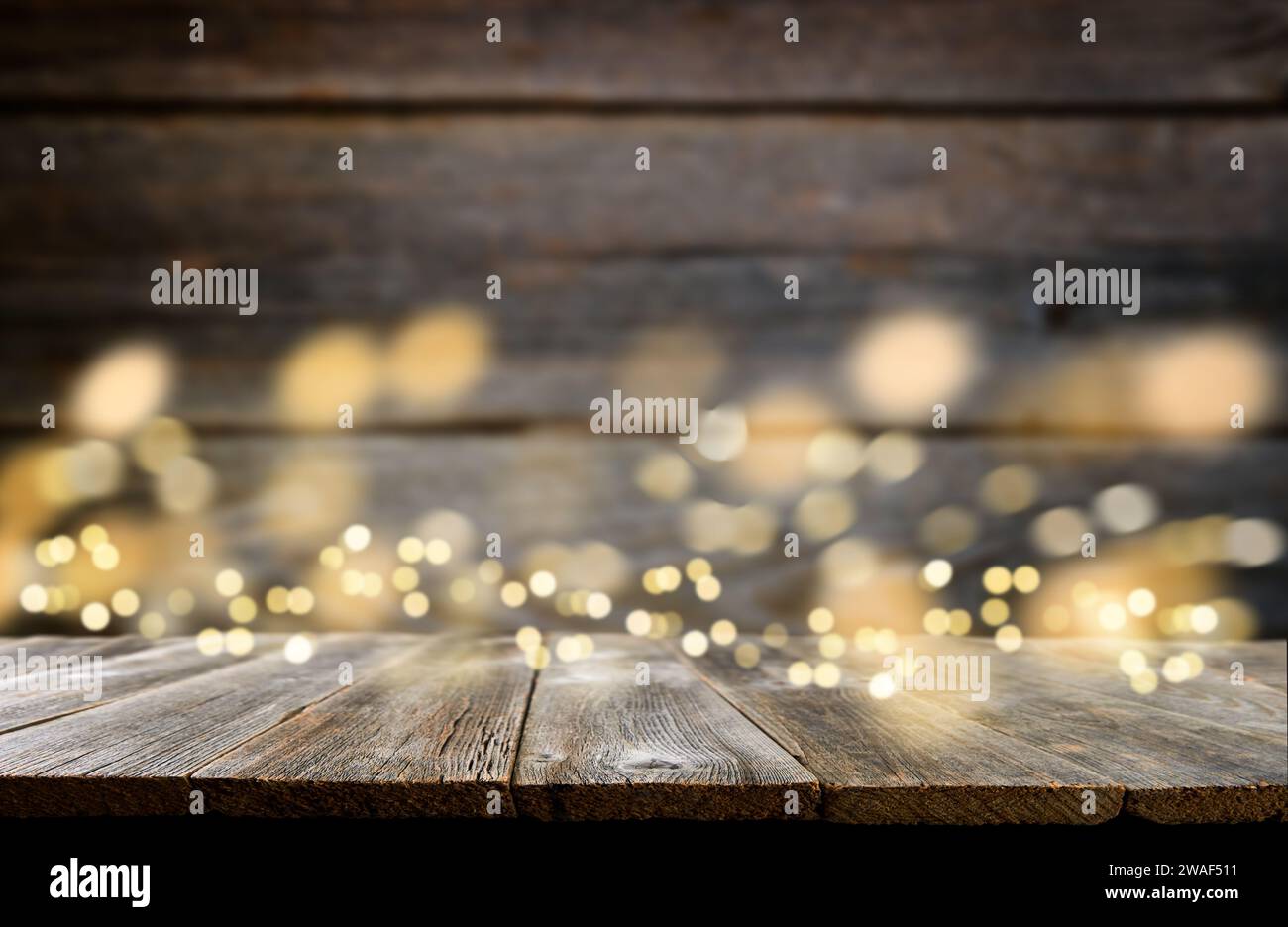 Empty rustic wooden table with blurred glitter lights background. Christmas lights on empty wooden table. Xmas holidays wallpaper. Stock Photo