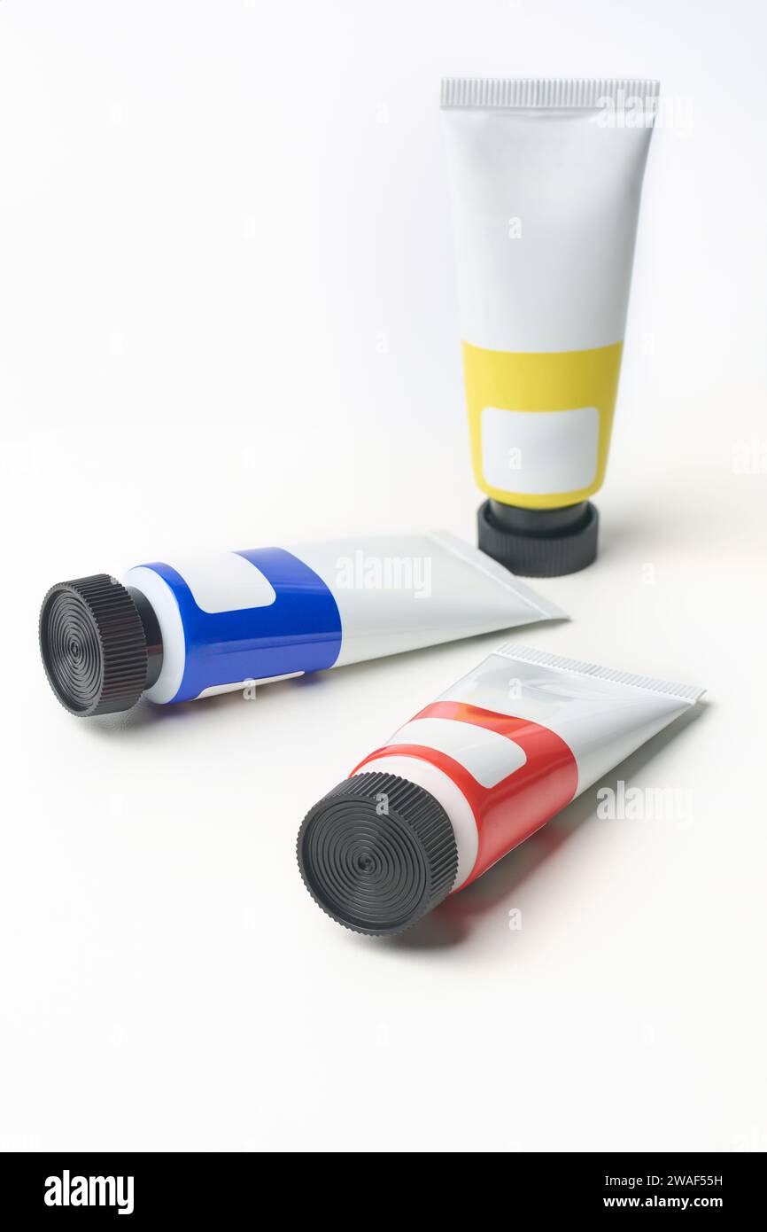 scattered artist's paint tubes with black cap isolated on white background, art supplies of primary colors blue, yellow and red, mock-up template Stock Photo